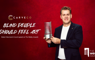 Robert Newman, Managing Director of Carveco, holding a Webby Award trophy against a red backdrop beside the statement “Blind People Should Feel Art,” his five-word speech delivered at the 30th Annual Webby Awards.